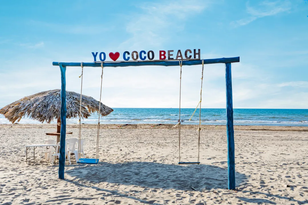 Columpios de madera frente al mar con el letrero Yo ❤ Coco Beach